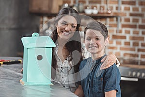 Little son and his beautiful mother smiling while looking at finished birdhouse