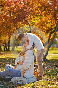 little son hugs his pregnant mom on the nature