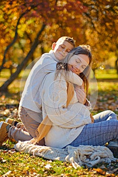 little son hugs his pregnant mom on the nature