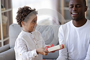 Little son making surprise gift for smiling African American father