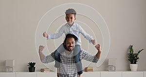 Little son sit on father shoulders smiling showing biceps