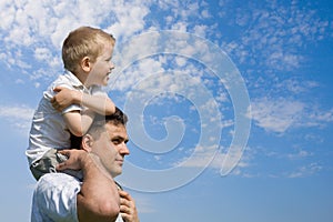 Little son sits on father`s shoulders