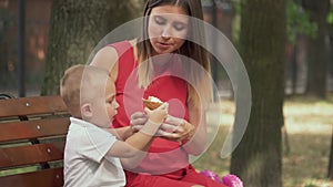 Little son treats his mother with ice cream in the park