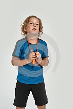 Little sportive boy child in sportswear looking aside while posing, standing with jump rope isolated over white