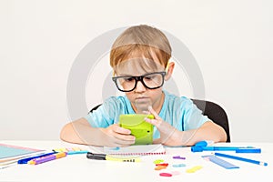 Little student boy counts something with calculator. Child doing homework at home. Preschool boy doing math exercise learning