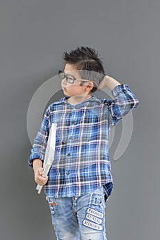 Little student boy feels nervous and thinking something, his hands hold the white books