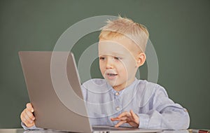 Little student boy using laptop computer in school class. Little funny programmer.