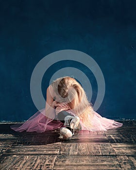 Little student girl of ballet school is crying sitting on floor because of been tired and failure of training