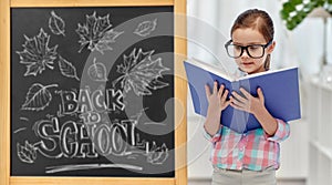 little student girl in eyeglasses reading book