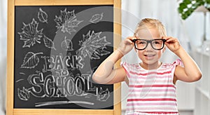 little student girl in glasses over chalkboard
