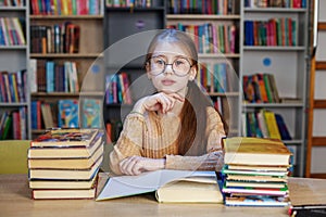 Little student girl with many books at school or library. Education and school concept