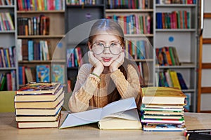 Little student girl with many books at school or library. Education and school concept