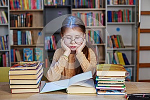 Little student girl with many books at school or library. Education and school concept