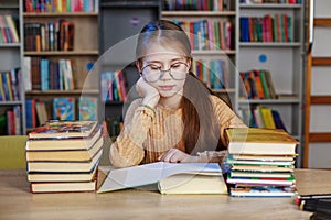 Little student girl with many books at school or library. Education and school concept