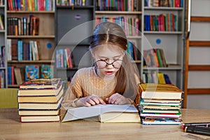 Little student girl with many books at school or library. Education and school concept