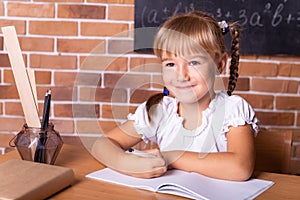 Little student girl sitting at a school desk and studying math. The child is doing homework. Preschool education