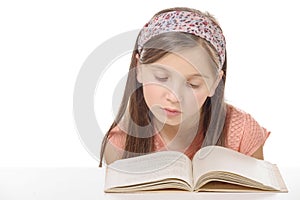 Little student girl studying and reading book at school