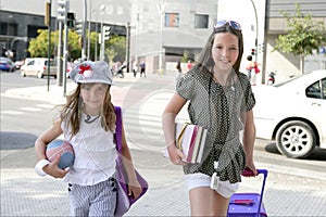 Little student girls going to school in city