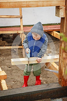 Little studious boy sawing a wooden board. Home construction. Li