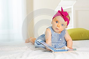 Little stylish baby girl leaf through book in bed