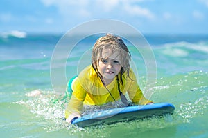 Little surfer learn to ride on surfboard on sea wave. Summer vacation with child. Kid girl is learning surfing, riding a