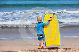 Little surfer run with bodyboard on sea beach