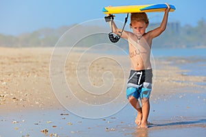 Little surfer run with bodyboard on sea beach