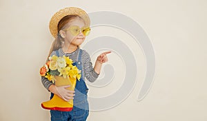Little surprised child girl in straw hat with a bouquet of yellow flowers in a rubber boot. Mommys little helper photo