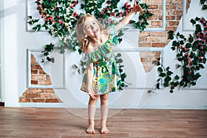 Little sweet girl will smile in the room decorated with flowers