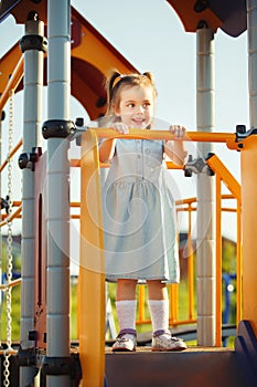 Little sweet happy girl on the hill in middle of playground.