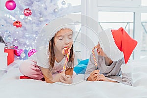 Little sweettooth siblings tasting delicious candies, enjoying the moment,  over white new year background.