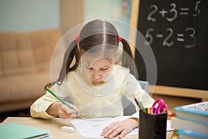 Little teacher. Beautiful young girl is teaching at home on blackboard.