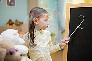 Little teacher. Beautiful young girl is teaching toys at home on