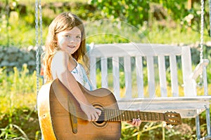 Little teen girl musician playing guitar. Dreamy kids face. Smiling child playing outdoors in summer.