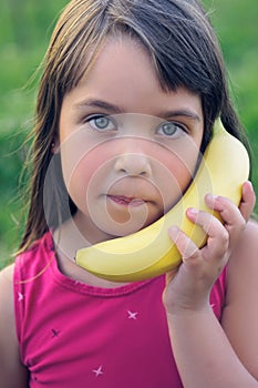 Little teen girl tries to speak by means of a banana instead of phone