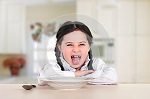 little teenage girl sitting at the dining table in the kitchen. Doesn\'t eat healthy food. No appetite