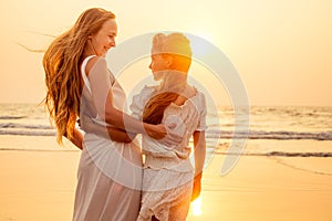 Little teenager cute girl and young mother at tropical beach enjoying the sunset on the sea tenderness and intimacy care