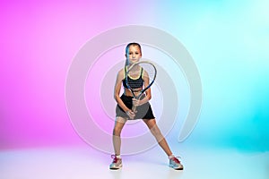 Little tennis girl in black sportwear  on gradient background in neon light
