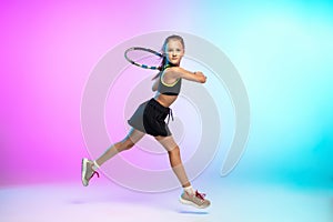 Little tennis girl in black sportwear  on gradient background in neon light