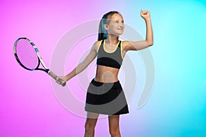 Little tennis girl in black sportwear isolated on gradient background in neon light