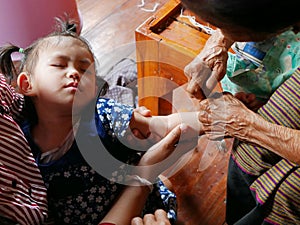 A little Thai baby girl falling asleep, while her great grandmother doing a blessing for her