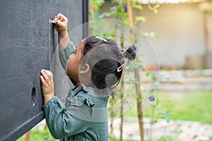 Little Thai girl writing the alphabet on a blackboard
