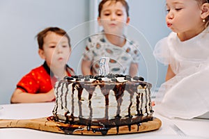 A little three-year-old girl blows out the candle on the cake