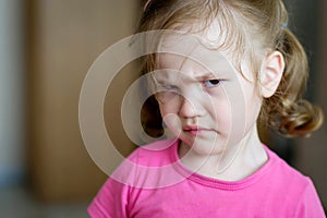 Little three year old girl looks angrily into the frame. Concept of a crisis of three years