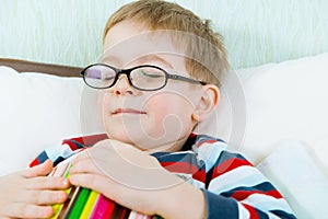 Little tired boy sleeping with book in bed