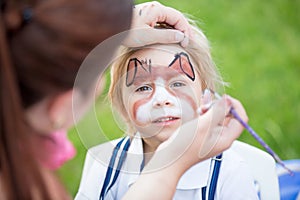 Little toddler baby boy, child with painted face as a dog, playing with pet dog in the garden