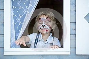 Little toddler baby boy, child with painted face as a dog, playing with pet dog in the garden