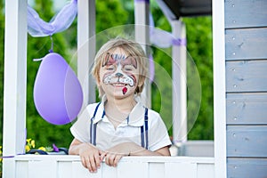 Little toddler baby boy, child with painted face as a dog, playing with pet dog in the garden