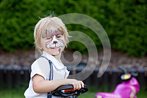 Little toddler baby boy, child with painted face as a dog, playing with pet dog in the garden