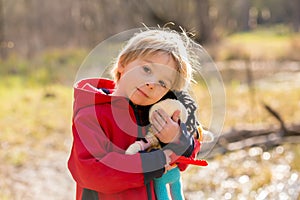 Little toddler blond child, boy, playing with handknitted doll